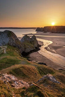 : Golden sunset over Three Cliffs Bay on the Gower Peninsula, South Wales, UK. Spring (March) 2022