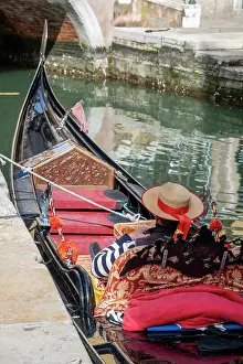 Gondolier Prints: Gondolier resting on a moored gondola boat, Venice, Veneto, Italy