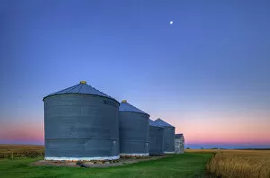 Agribusiness Gallery: Grain bins at dawn with moon near Swift Current Saskatchewan, Canada