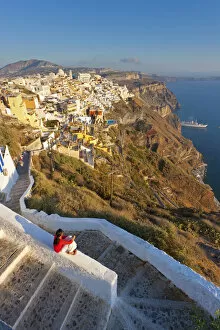 Greece, The Cyclades, Santorini (Thira), Fira, Woman sitting on wall in town (MR)