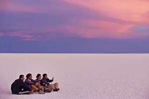 A group of tourists sit on the great expanse of salt