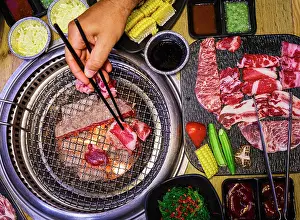 Ingredient Prints: Hand placing meat on a grill with vegetables and sauces, Vietnam