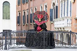 Heart-shaped costume standing on a bridge at the Venice Carnival, Venice, Italy
