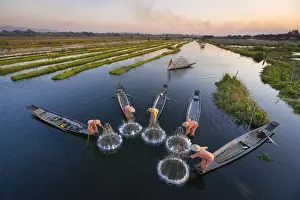 High angle of five traditional fishermen fishing together using conical nets, Lake Inle