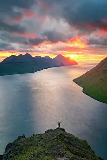 One Person Prints: High angle view of a man silhouette rejoicing on Klakkur mountain looking at sea at sunset