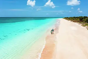 Two People Prints: High angle view of man and woman in love embracing on a beach while looking at Caribbean sea