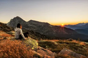 Hiker with dog admire sunset over Fiemme valley, Trentino Alto Adige, Italy Hiker with dog admire sunset over Fiemme valley, Trentino Alto Adige, Italy