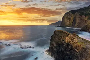 Long Exposure Prints: Hiker with head torch admiring sunrise from cliffs at Miradouro Do Guindaste viewpoint