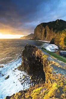 Images Dated 15th October 2021: Hiker looking at the crashing waves at dawn from cliffs, Madeira, Portugal (MR)