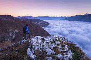 Above The Clouds Prints: Hiker over the top looks lake Como (ramo di Lecco) covered by the fog at sunrise