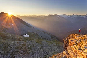 Hiker observes the sunrise from the summit of PeterskAA┬Âpfl, Zillertal Alps, Tyrol