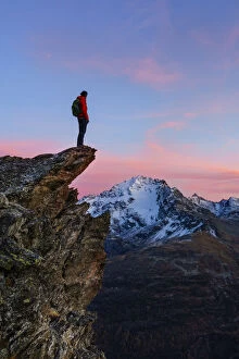 An hiker on a rock with a panoramic view at sunset. Valdidentro, Valtellina, Lombardy