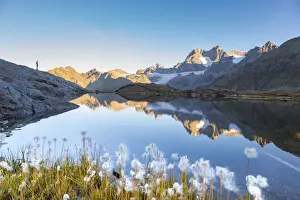 Trekker Prints: Hiker silhouette along an alpine lake during summer in italian Alps mountains