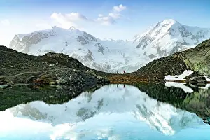Two People Prints: Hikers walking on mountain ridge lakeshore with the snowcapped Lyskamm and Breithorn on background