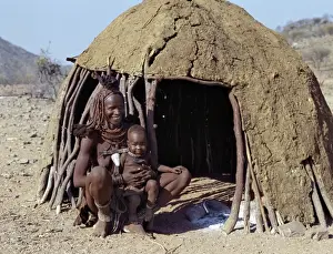 Beaded Jewellery Prints: A Himba mother and baby son relax outside their dome-shaped home