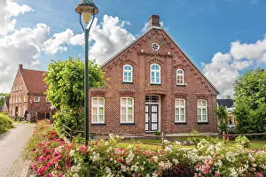 Krummhorn Prints: Historic brick house and lush floral decorations in the village of Rysum