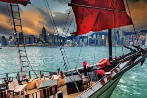 Hong Kong, tourist on a junk boat in Victoria harbor at sunset with Marina buildings