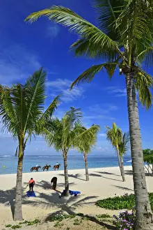 Horse riders on the beach in front of a luxury hotel on the Le Morne Peninsula, Mauritius