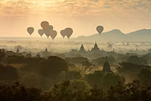 Images Dated 30th March 2017: Hot air balloons fly over the temples of Bagan at sunrise on a misty morning, Myanmar