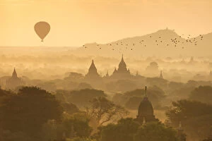 Images Dated 30th March 2017: Hot air balloons fly over the temples of Bagan at sunrise on a misty morning, Myanmar