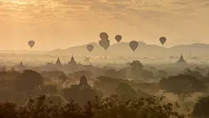 Hot air balloons fly over the temples of Bagan at sunrise on a misty morning, Myanmar