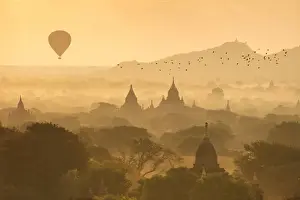 Hot air balloons fly over the temples of Bagan at sunrise on a misty morning, Myanmar
