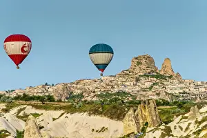 Hot air balloons at sunrise with mountain village of Ortahisar in the background