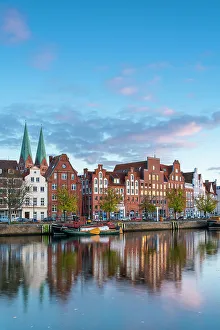 Houses on riverfront of Trave river with towers of St. Marienkirche church in background at sunset, Lubeck, UNESCO, Schleswig-Holstein, Germany