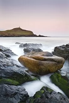 Huge granite boulder lodged on the shores of Porth Ledden at dawn, Cornwall, England