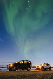 Night Sky Prints: Iceland, Europe. Cars with lights on at night under a starry sky and the northern lights