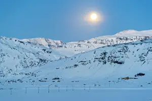 Iceland, Europe. Lonely house on the mountains in a winter landscape with full moon