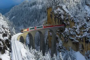 Iconic swiss red Bernina Express train in winter landscape and pristine snow. Swizerland Iconic swiss red Bernina Express train in winter landscape and pristine snow. Swizerland