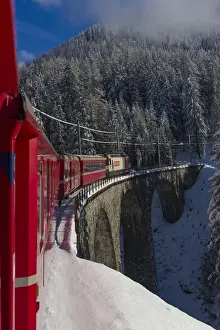 Iconic swiss red Bernina Express train in winter landscape and pristine snow. Swizerland