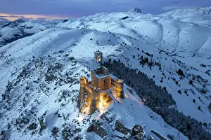 Building Exterior Prints: Illuminated high angle view of the castle of Rocca Calascio and the church Santa Maria della Pieta at dusk