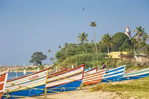 India, Kerala, Kollam, Fishing boats on beach with Tangasseri Lighthouse in background