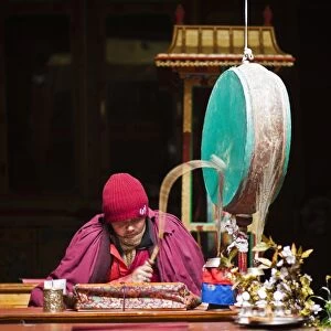India, Ladakh, Hemis. Monk reciting prayers to the slow rhythm of a drum at Hemis Monastery