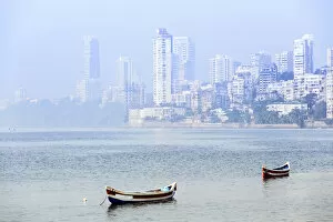 India, Maharashtra, Mumbai, fishing boats floating on the Arabian sea with the skyscrapers