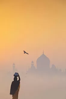 Images Dated 9th February 2018: India, water carrying a water pot on a foggy morning with the sun rising on the Taj Mahal