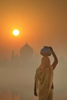 Images Dated 9th February 2018: India, water carrying a water pot on a foggy morning with the sun rising on the Taj Mahal