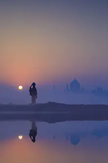 Agra Prints: India, water carrying a water pot on a foggy morning with the sun rising on the Taj Mahal