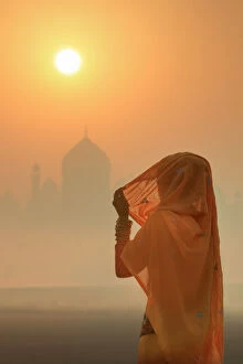 Images Dated 9th February 2018: India, woman wearing a traditional sari on a foggy morning with the Taj Mahal in