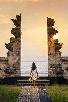 Gate Prints: Indonesia, Bali, Candidasa. A young woman walking through the doorway of a traditional