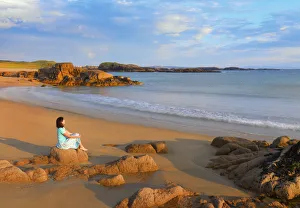 Codonegal Prints: Ireland, Co. Donegal, Cruit island, woman sitting on rocks (MR)