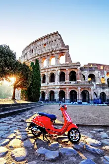 Italy, Rome, a red Vespa motorbike in front of Colosseum at sunrise
