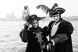Two People Prints: Italy, Veneto, Venice, a black and white version of a couple in costume in front of Salute during the Venice Carnival