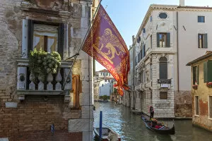Images Dated 5th January 2015: Italy, Veneto, Venice. Gondola passing on a canal with venetian flag hanging from a wall
