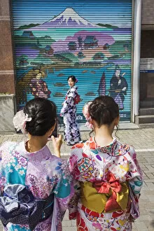 Japan, Honshu, Tokyo, Asakusa, Young Women in Kimono Taking Photos in Front of Shop