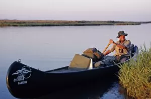 Zimbabwe Collection: John Stevens paddling his canoe on the Zambezi at sunset