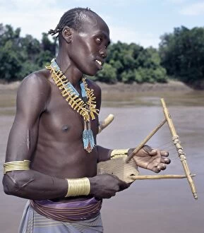 Beaded Necklaces Collection: A Karo man with braided hair plays a traditional stringed