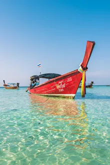 Ko Lipe, Satun Province, Thailand. Red wooden long tail boat on turquoise water